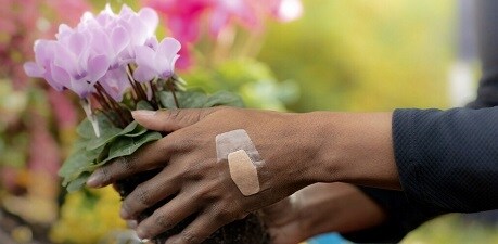 femme cueillant des fleurs avec un pansement waterproof sur la main
