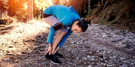 Femme vérifiant sa cheville tout en courant

