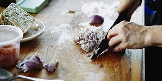 personne coupant un oignon avec un couteau
