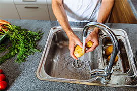 femme lavant des pommes de terre dans le lavabo